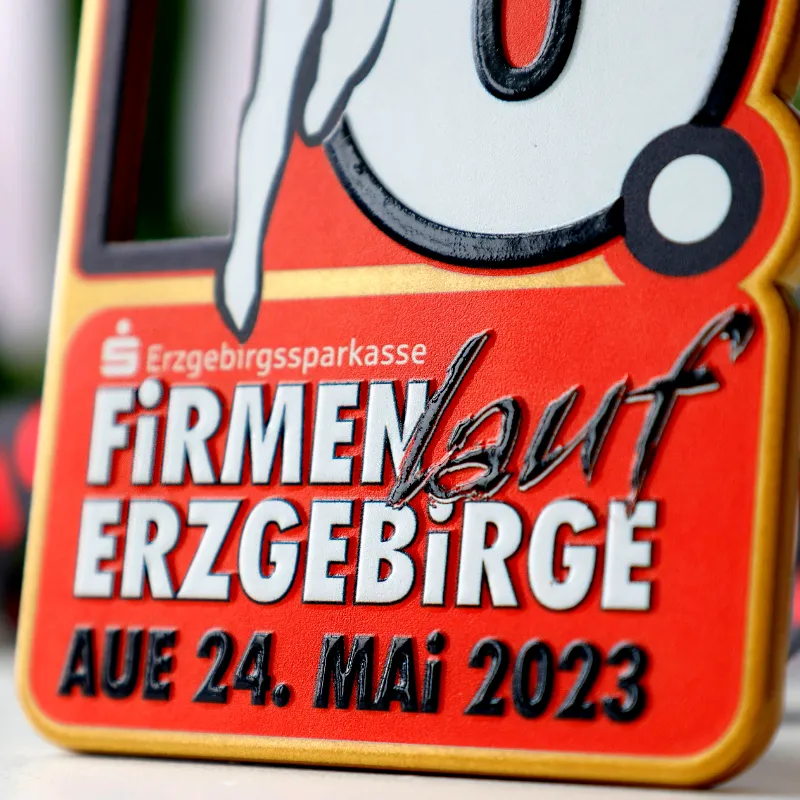 Close-up of a Firmenlauf Erzgebirge 2023 medal featuring embossed lettering and vibrant colours.