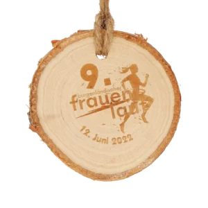 A round wooden medal for the 9th Frauenlauf event, featuring an engraved silhouette of a runner.