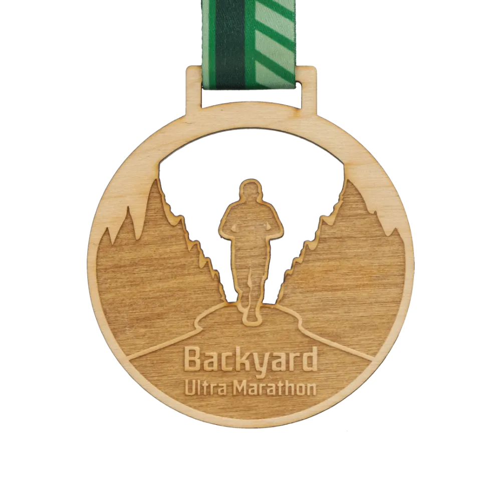 Medaglia rotonda in legno Backyard Ultra Marathon con silhouette ritagliata di un corridore e nastro verde a motivi.